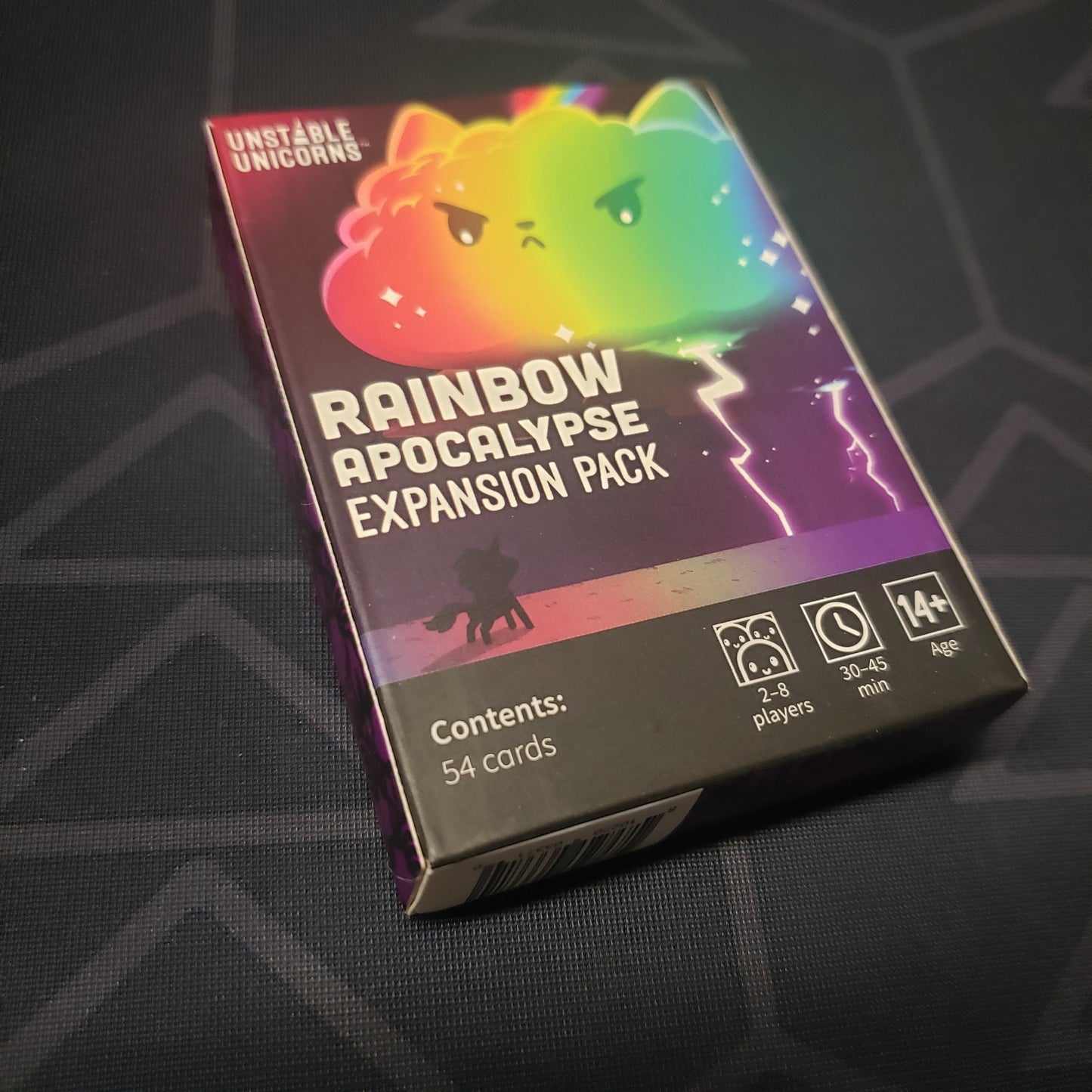 Image shows the front cover of the box of the Rainbow Apocalypse expansion for the card game Unstable Unicorns