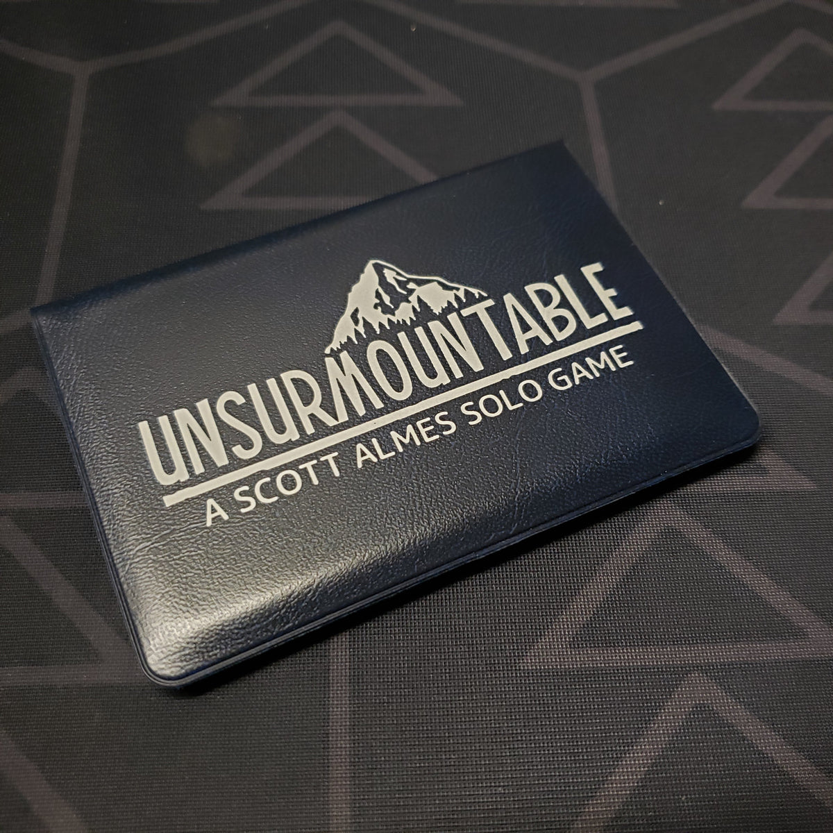 Image shows the front of the card wallet for the Unsurmountable card game