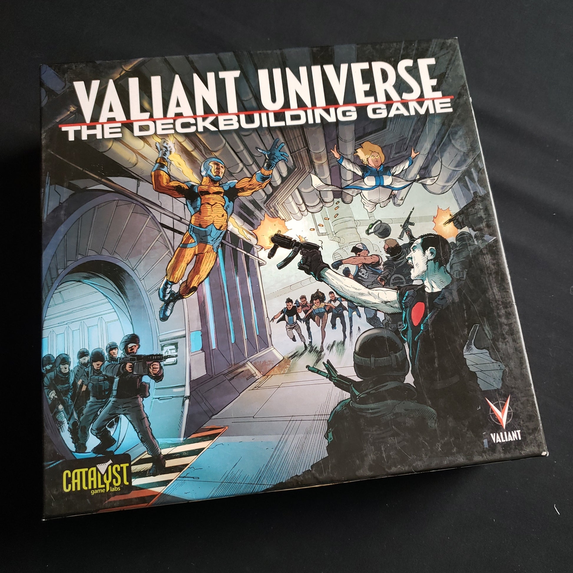 Image shows the front cover of the box of the Valiant Universe Deckbuilding game