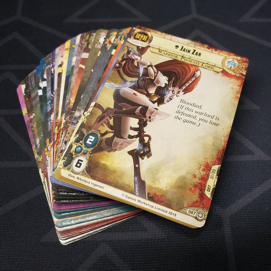Image shows the cards for the Against the Great Enemy expansion for the card game Warhammer 40K Conquest fanned out in a stack