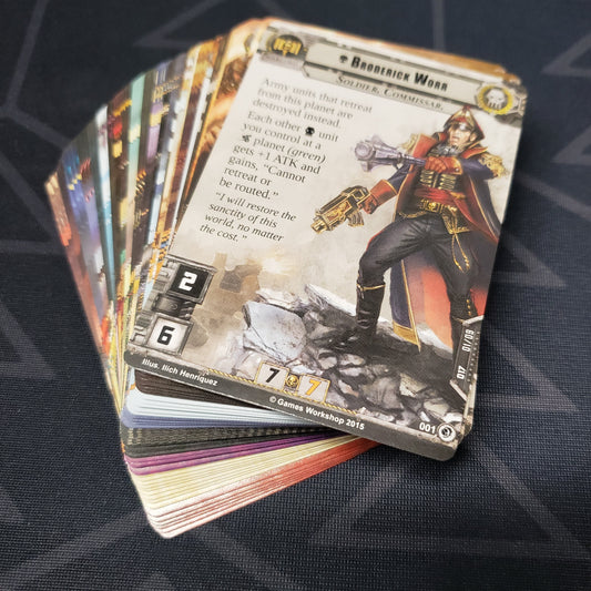 Image shows the cards for the Decree of Ruin expansion for the card game Warhammer 40K Conquest fanned out in a stack