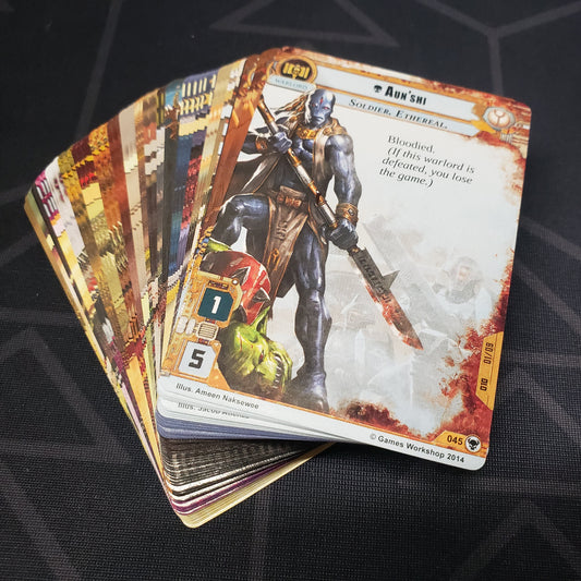 Image shows the cards for the Gift of Ethereals expansion for the card game Warhammer 40K Conquest fanned out in a stack