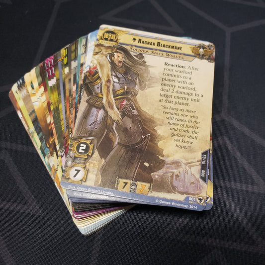 Image shows the cards for the Howl of Blackmane expansion for the card game Warhammer 40K Conquest fanned out in a stack