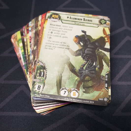 Image shows the cards for the Searching For Truth expansion for the card game Warhammer 40K Conquest fanned out in a stack