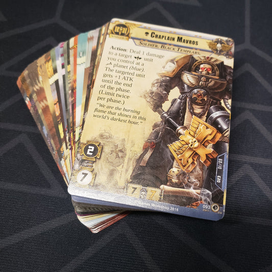 Image shows the cards for the Wrath of the Crusaders expansion for the card game Warhammer 40K Conquest fanned out in a stack