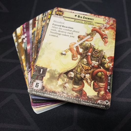 Image shows the cards for the Zogwort's Curse expansion for the card game Warhammer 40K Conquest fanned out in a stack