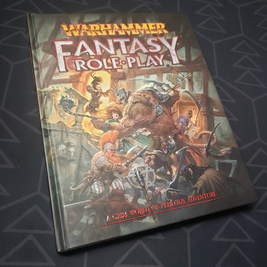 Image shows the front cover of the core rulebook for the roleplaying game Warhammer Fantasy Roleplay 4E