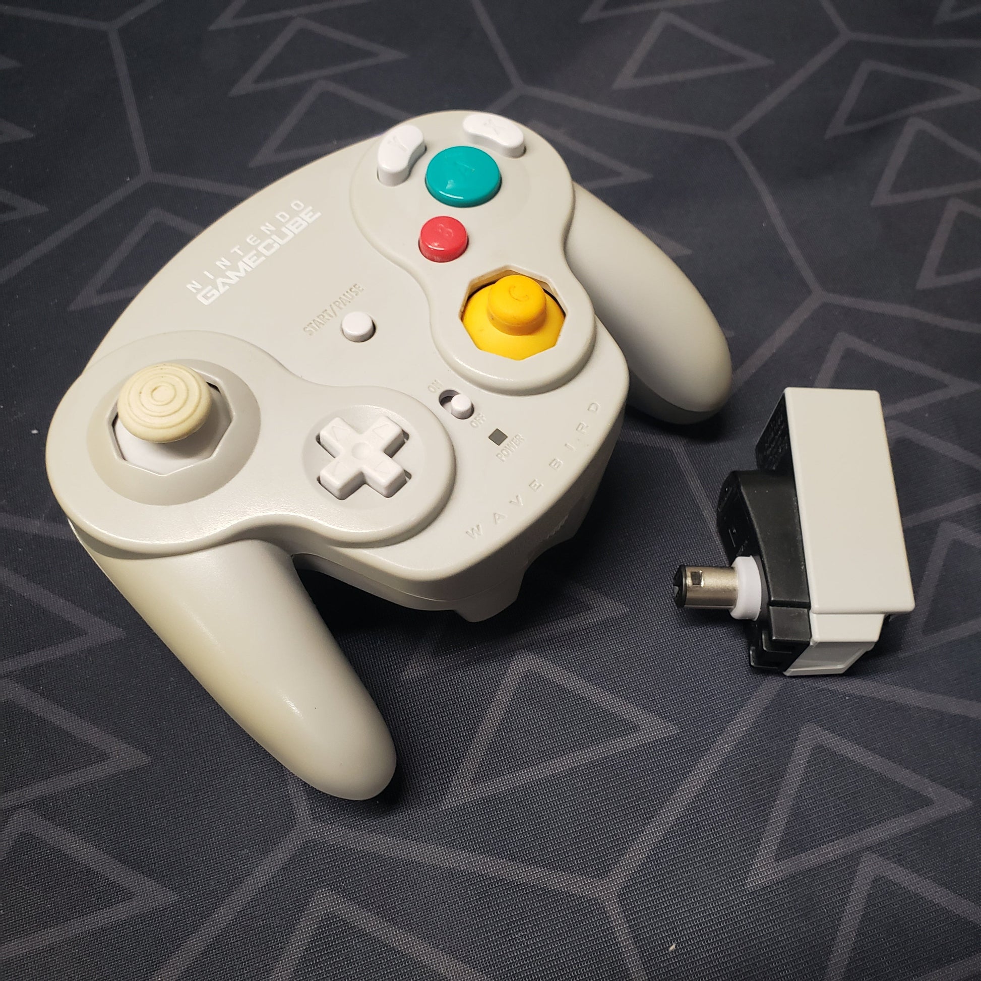 Image shows a Wavebird Wireless gaming controller for the GameCube with its receiver