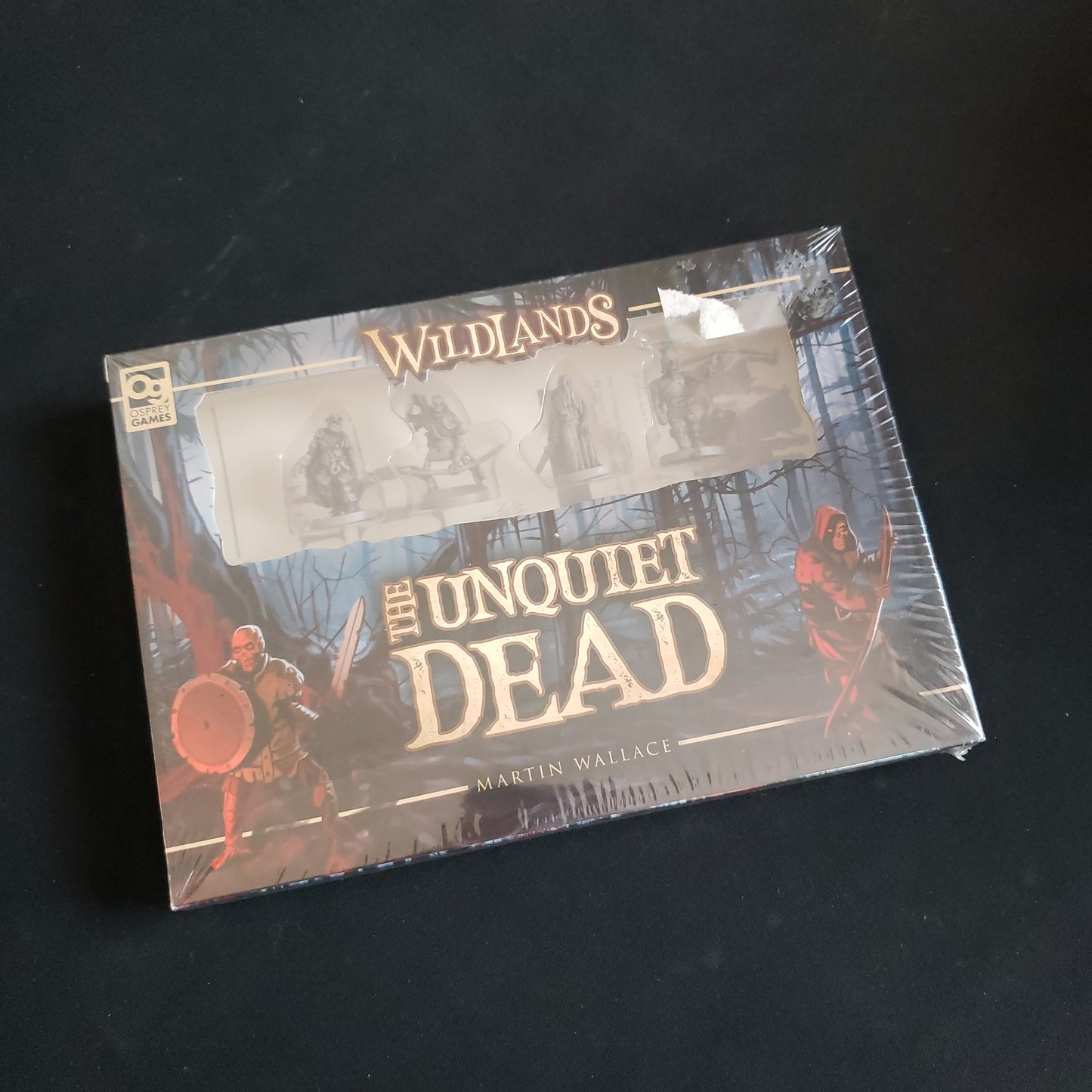 Image shows the front cover of the box of the Unquiet Dead expansion for the Wildlands board game