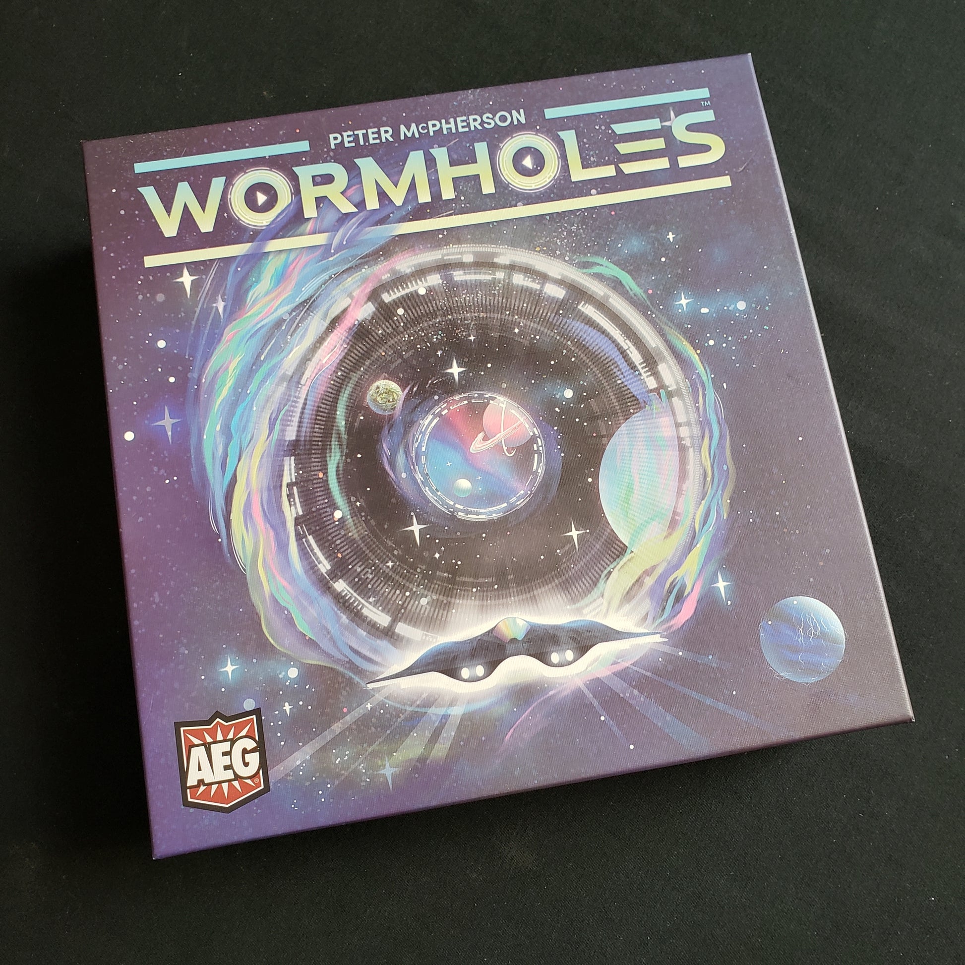 Image shows the front cover of the box of the Wormholes board game