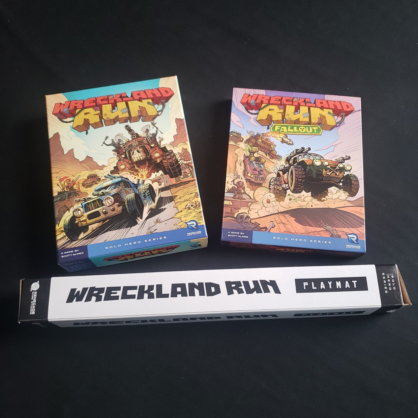 Image shows the front of the boxes for the board game Wreckland Run, its Fallout expansion, and the playmat