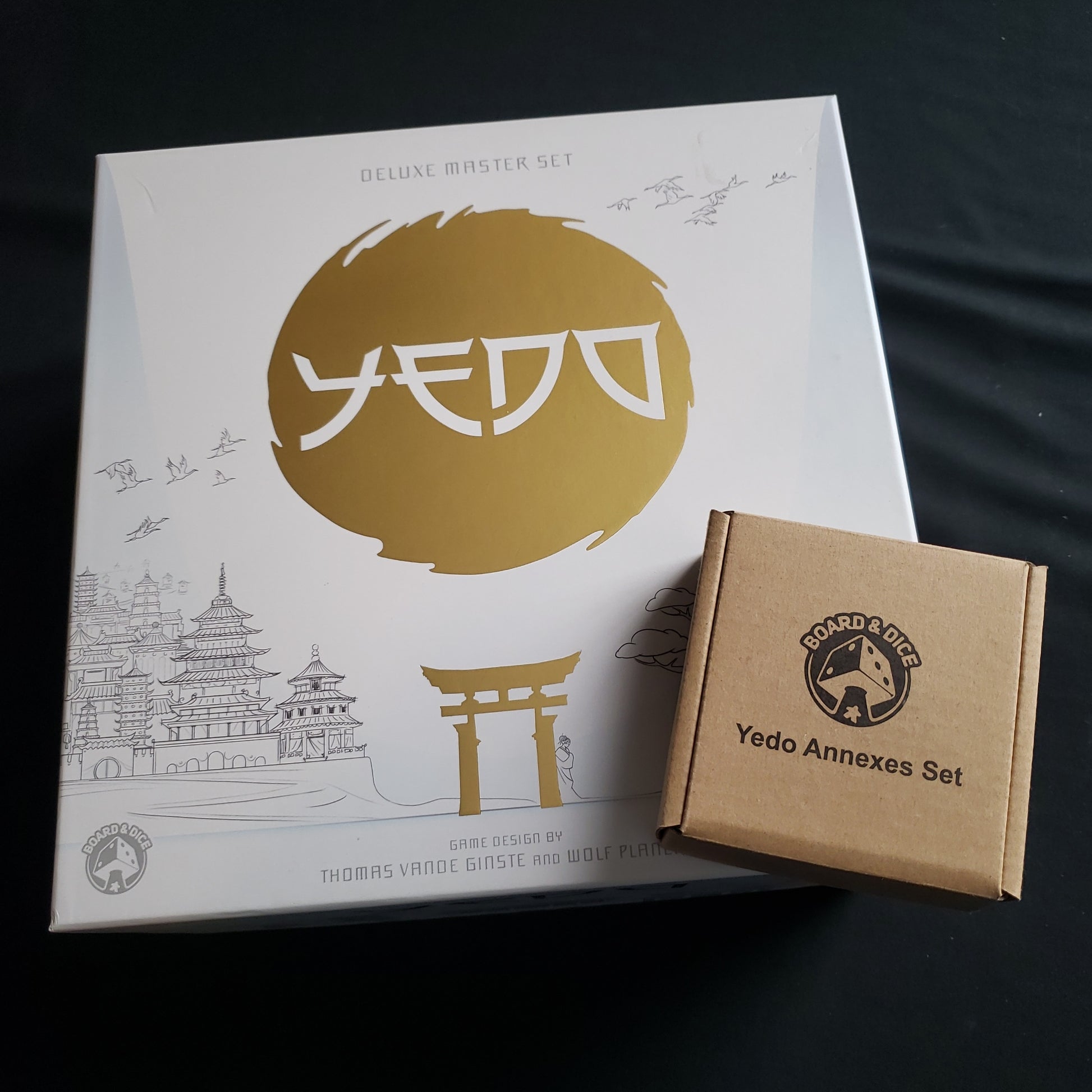 Image shows the front cover of the box of the Yedo: deluxe Master Set board game, with the Annexes Set box sitting on top of it