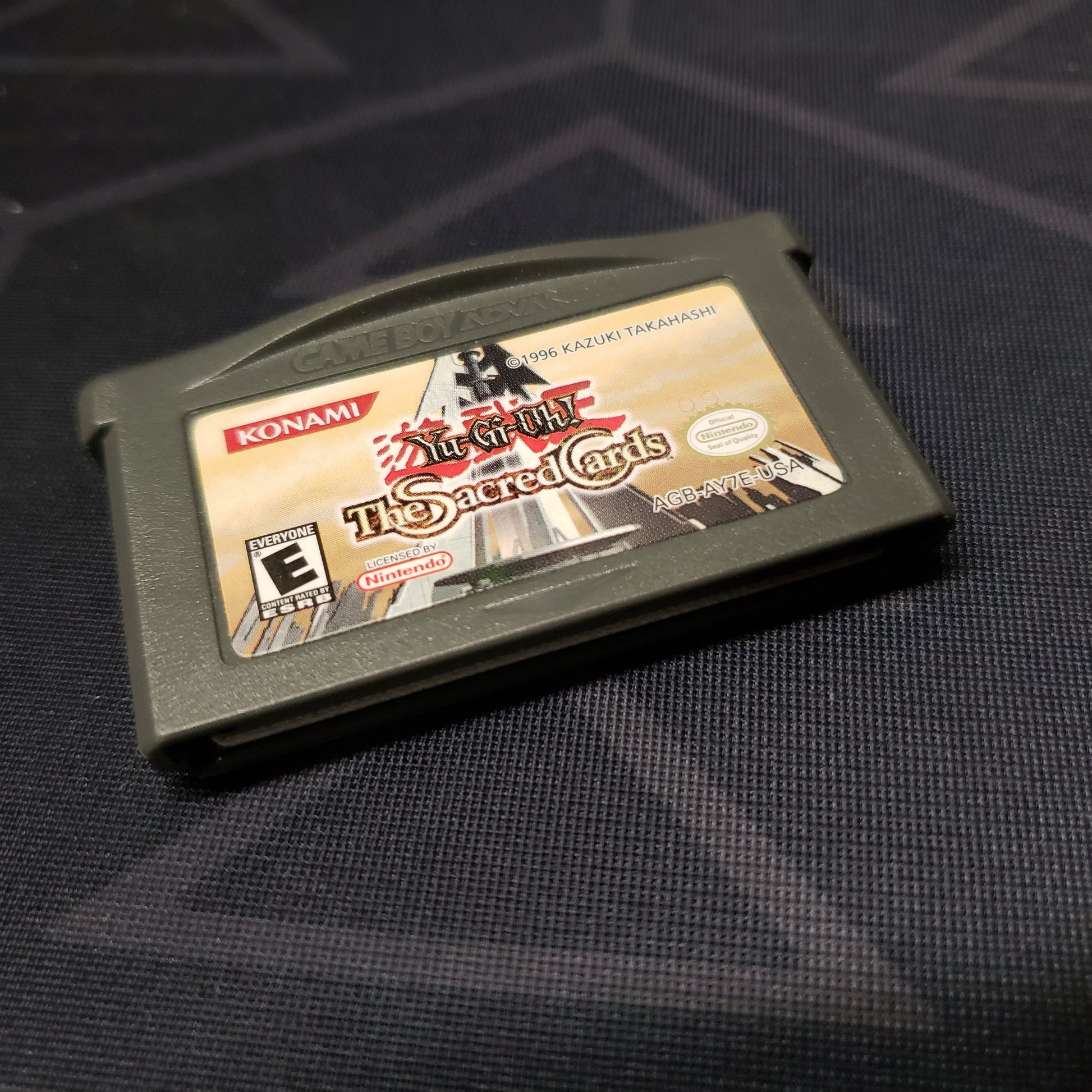 Image shows the front of the cartridge for the video game Yu-Gi-Oh!: The Sacred Cards for Nintendo Game Boy Advance