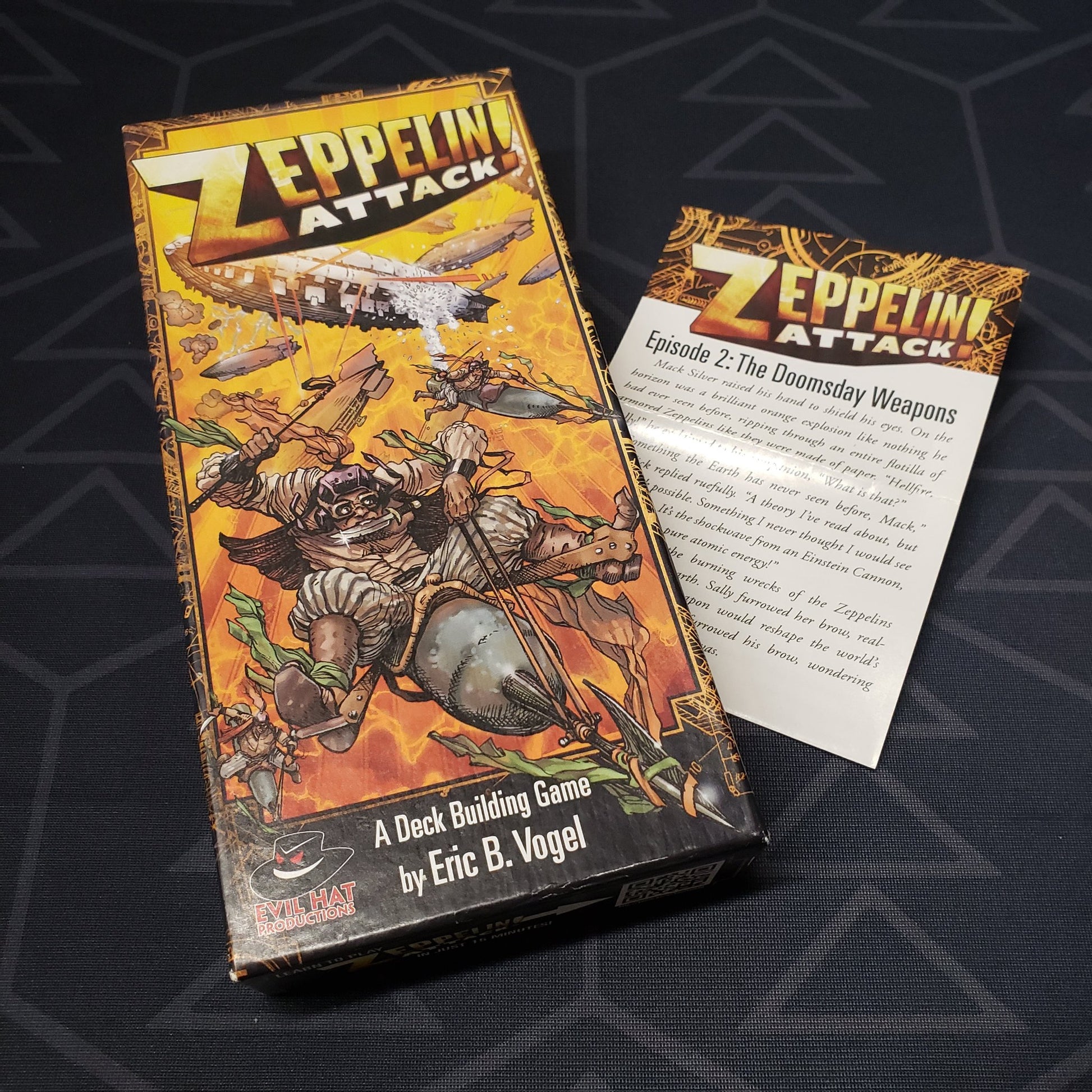 Image shows the front cover of the box of the Zeppelin Attack! card game, sitting on top of the instructions for the Doomsday Weapons expansion