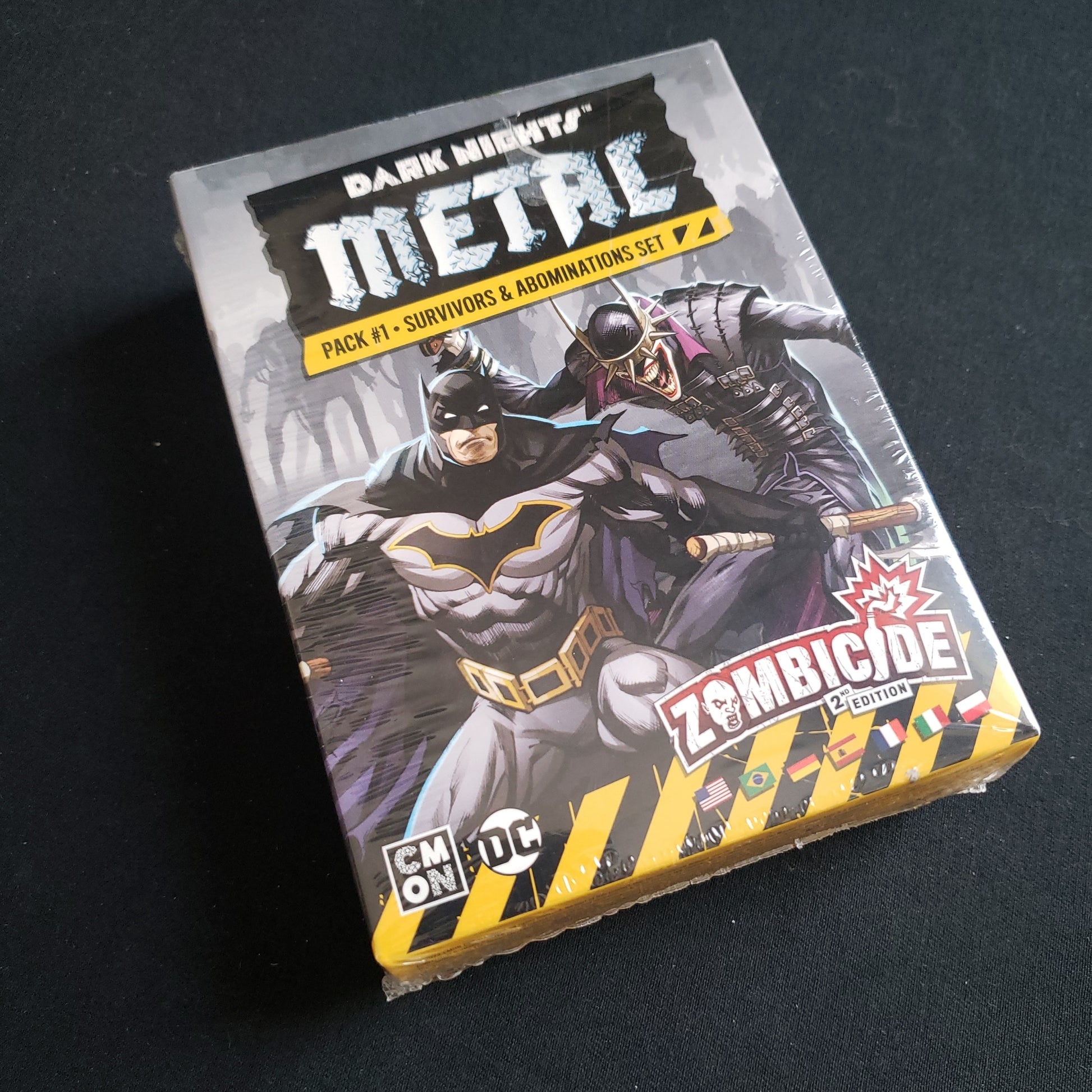 Image shows the front cover of the box of the Dark Nights Metal Pack 1 expansion for the board game Zombicide