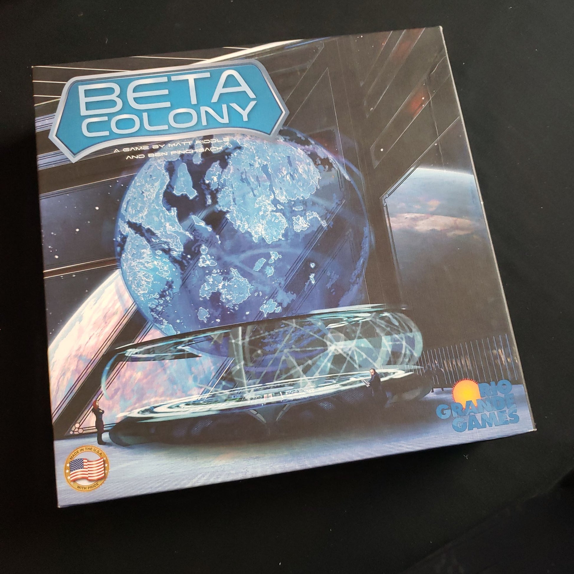 Image shows the front cover of the box of the Beta Colony board game