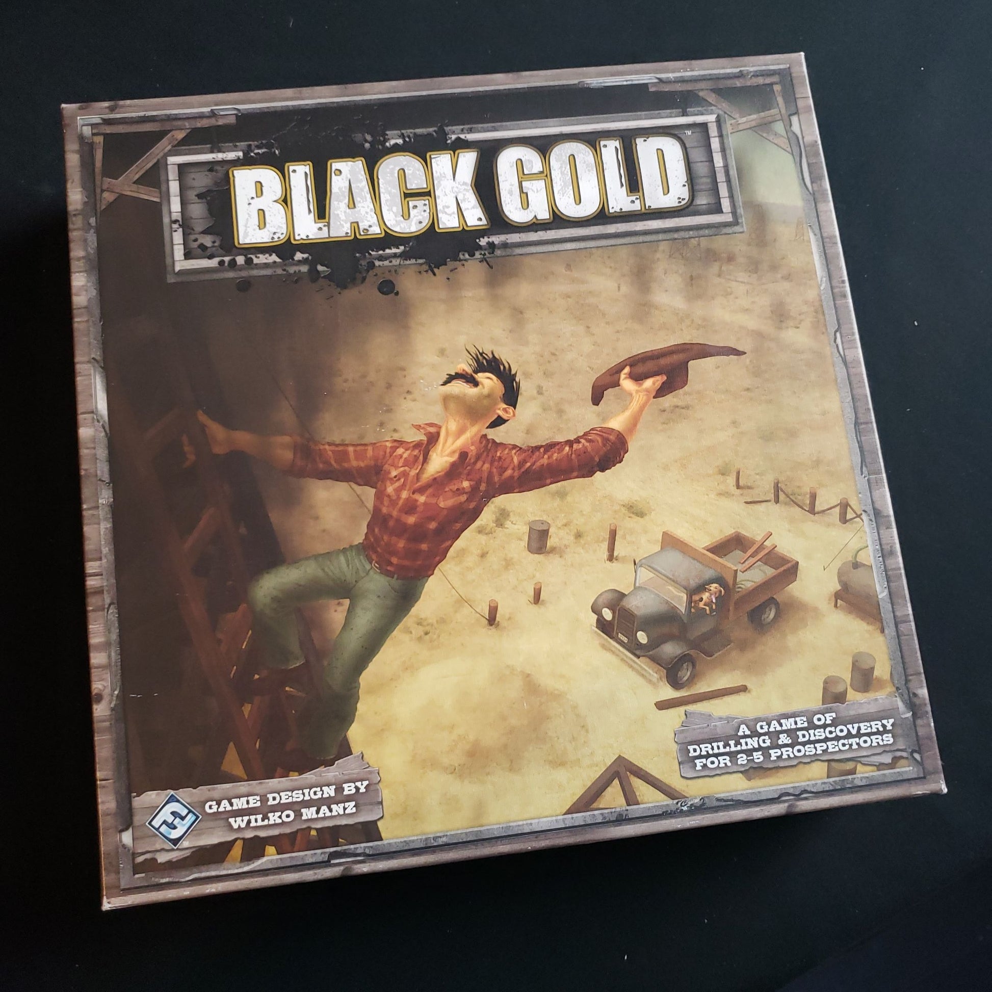 Image shows the front cover of the box of the Black Gold board game