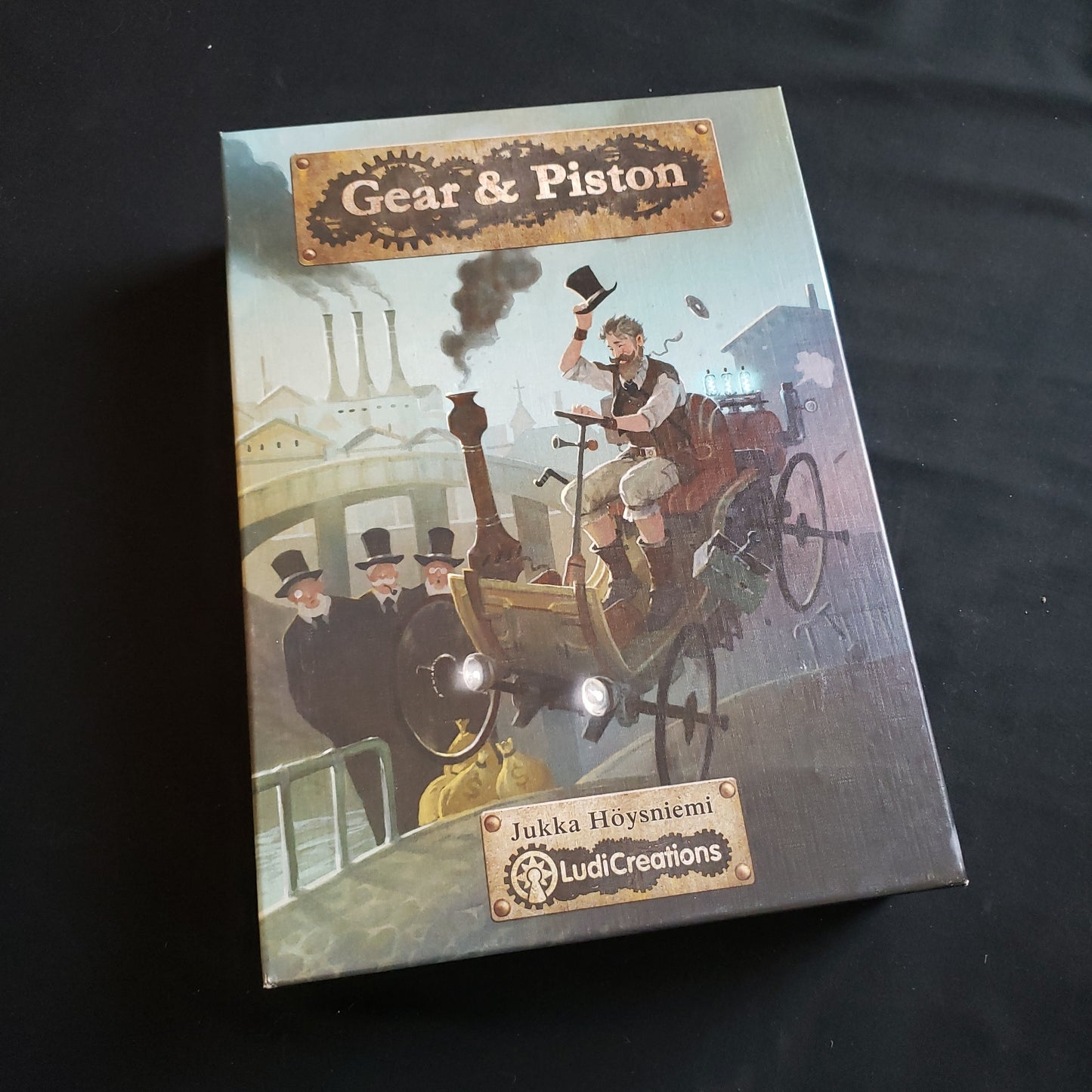 Image shows the front cover of the box of the Gear & Piston board game