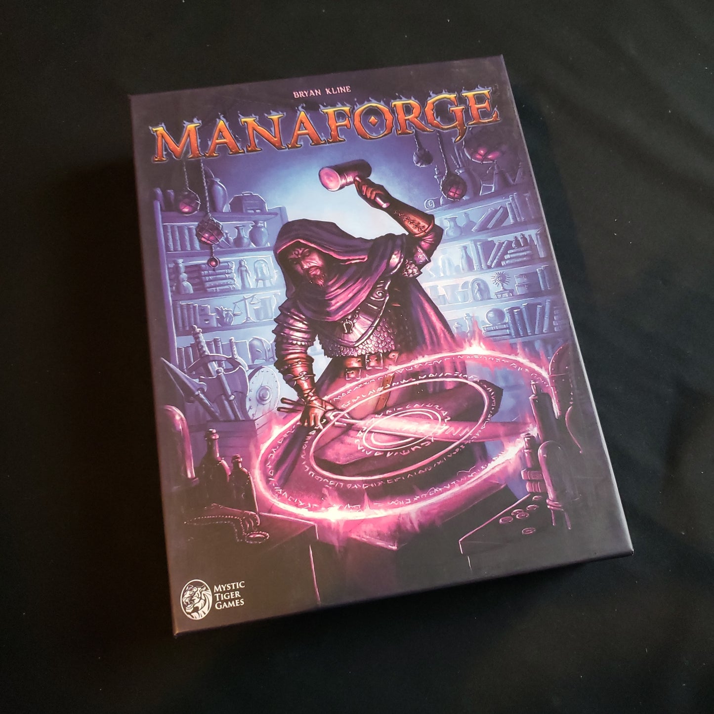 Image shows the front cover of the box of the Manaforge board game