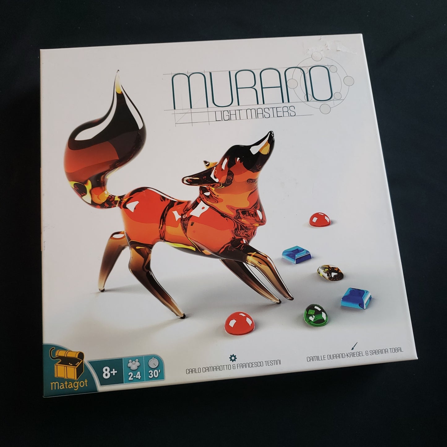 Image shows the front cover of the box of the Murano: Light Masters board game
