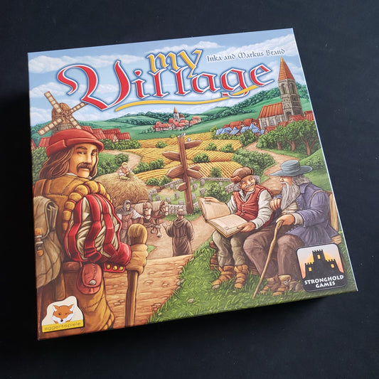Image shows the front cover of the box of the My Village board game