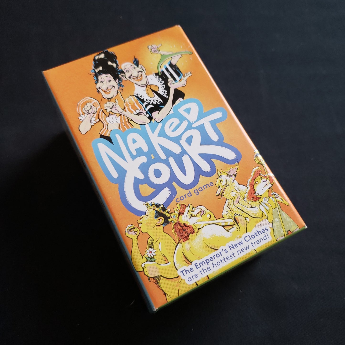 Image shows the front cover of the box of the Naked Court card game