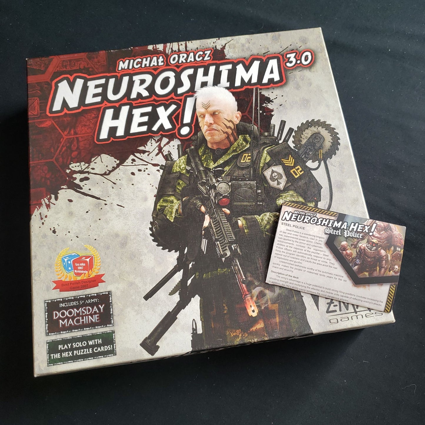 Image shows the front cover of the box of the Neuroshima Hex! 3.0 board game with the instructions for the Steel Police expansion on top of the box