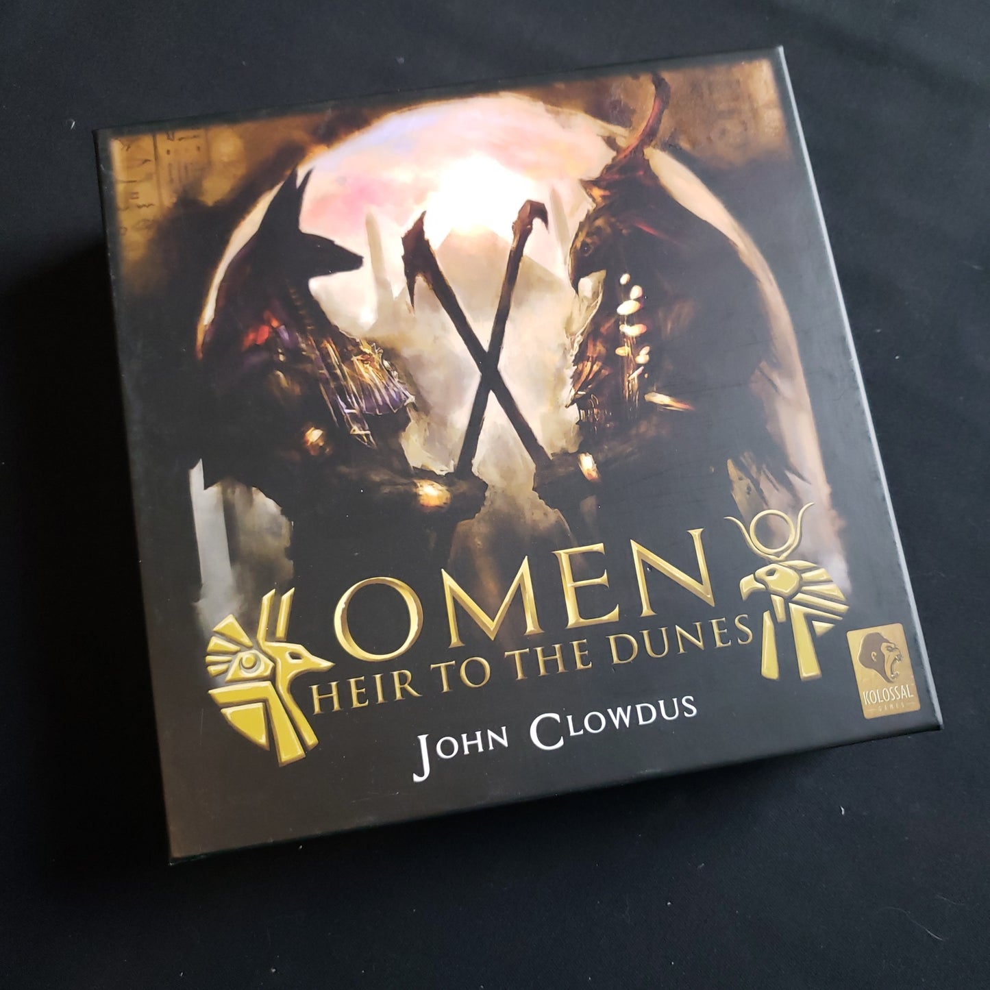 Image shows the front cover of the box of the Omen: Heir to the Dunes card game