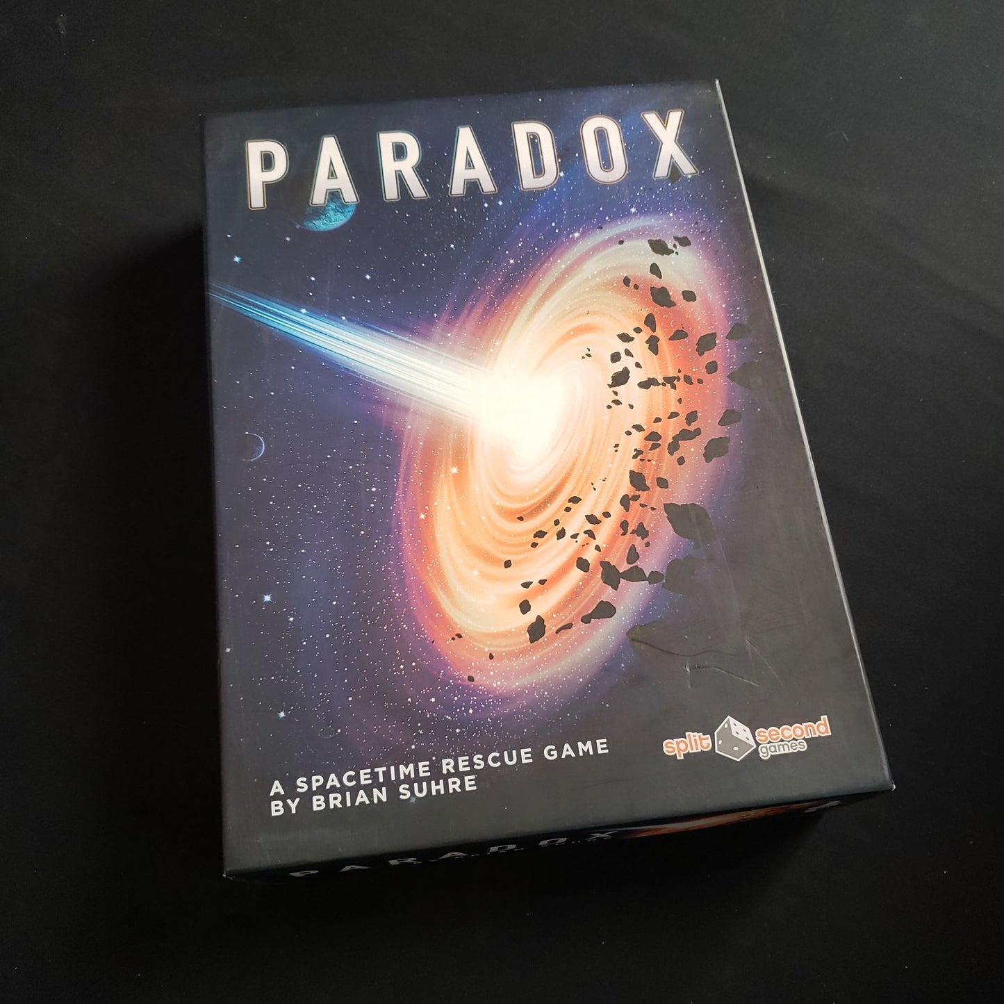 Image shows the front cover of the box of the Paradox board game