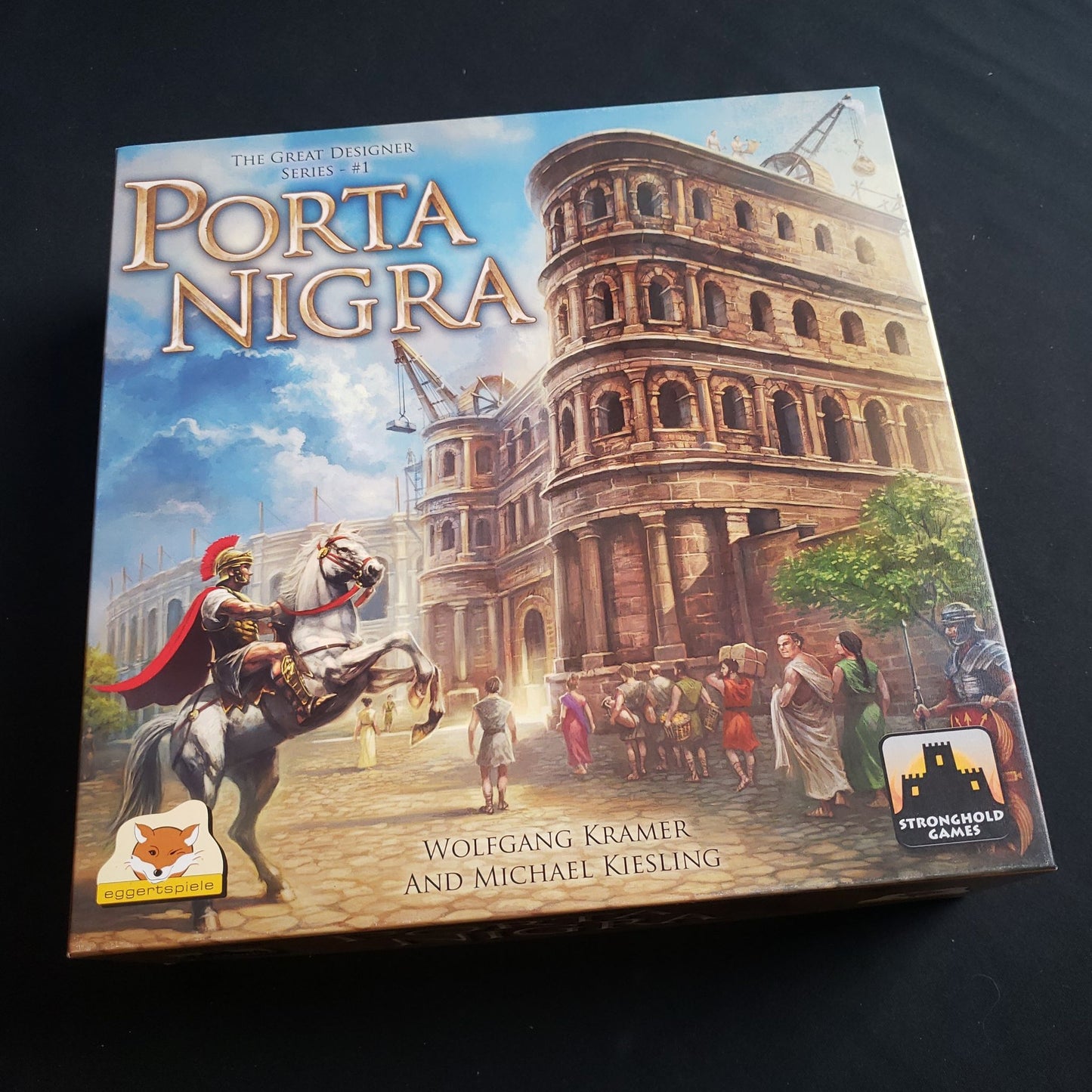 Image shows the front cover of the box of the Porta Nigra board game