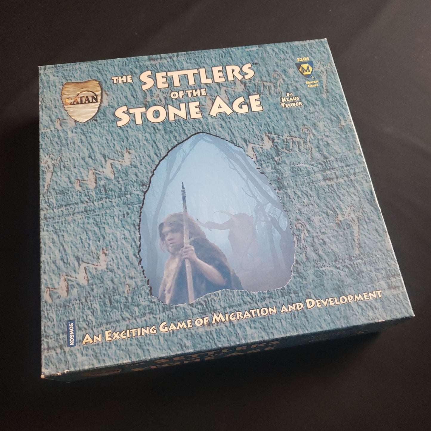 Image shows the front cover of the box of the Settlers of the Stone Age board game